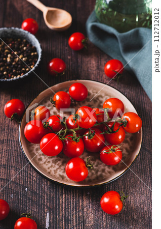 Plate with fresh cherry tomatoes on a wooden table vertical view Plate with fresh cherry tomatoes on a wooden table vertical view 112712012