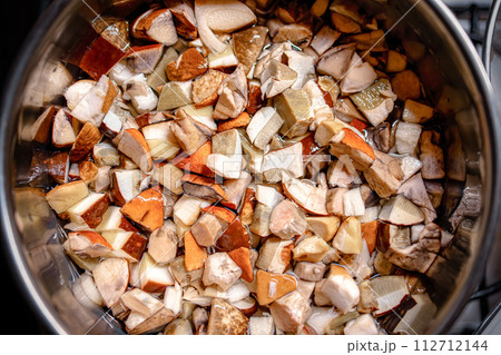 chopped wild mushrooms (cep, porcini, Boletus edulis, penny bun) are cooked in a saucepan. cooking mushroom soup. traditional and favorite autumn dish in Russia. Flat laid. 112712144