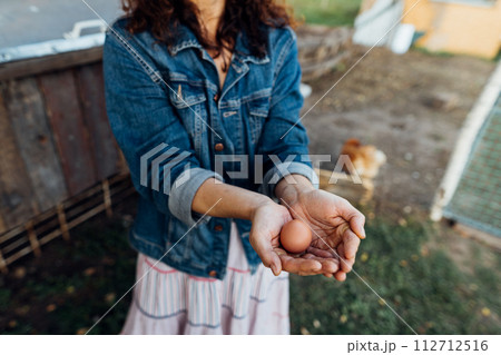Fresh organic eggs in female hands on a private farm. A woman exhibits sheer happiness with a fresh egg in hand, standing on her farm Sustainable lifestyle, organic farmer 112712516