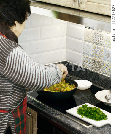 Elderly Woman Cooking Vegetables 112712627