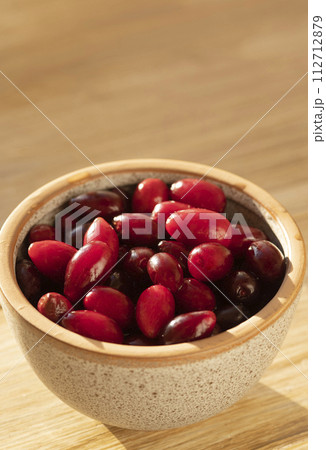 Fresh ripe dogwood berries in bowl on wood table, closeup Fresh ripe dogwood berries in bowl on wood table, closeup 112712879