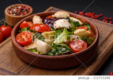 Delicious fresh caprese salad with mozzarella, tomatoes, greens with salt, spices and herbs Delicious fresh caprese salad with mozzarella, tomatoes, greens with salt, spices and herbs 112713200