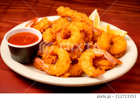 Fried prawns with spice and lemon on a white plate with pineapple on wooden table. Grilled seafood like shrimps 112713351