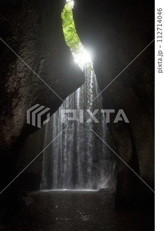 An incredibly beautiful waterfall in a cracked rock in the jungle on the popular island of Bali. An incredibly beautiful waterfall in a cracked rock in the jungle on the popular island of Bali. 112714046