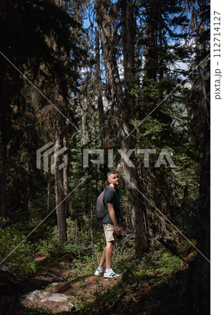 A man sits in a rocking-egg in a straw pergola enjoying the sunset 112714127