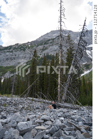 A man sits in a rocking-egg in a straw pergola enjoying the sunset 112714128