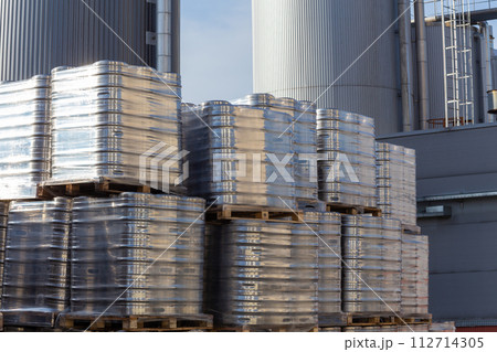Large amount of aluminium beer kegs stacked on each other with euro palettes and wrapped around with vinyl foil. 112714305