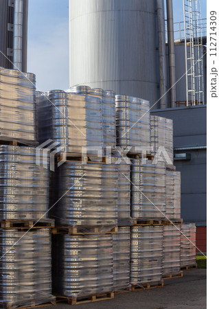 Large amount of aluminium beer kegs stacked on each other with euro palettes and wrapped around with vinyl foil. 112714309
