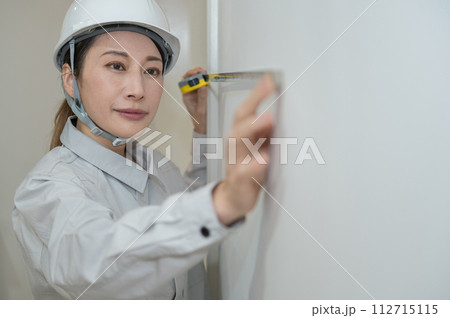 巻き尺で長さを計測するエンジニアの女性 112715115
