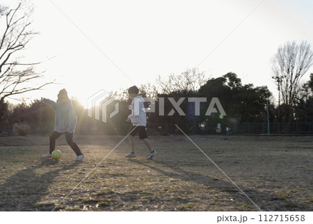 夕暮れまでサッカーを楽しむ子どもたち 夕暮れまでサッカーを楽しむ子どもたち 112715658
