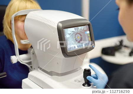 Patient during visit to optometrist for microscopic analysis of eyelids, sclera, conjunctiva, iris, lens, cornea. Examining of fundus of mature woman by ophthalmologist using retinal scanner 112716250