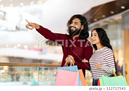 Eastern man and woman enjoying season sale at shopping mall Eastern man and woman enjoying season sale at shopping mall 112717543