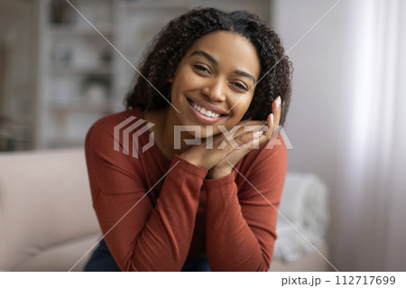 Beautiful black woman with curly hair smiling and resting head on hands Beautiful black woman with curly hair smiling and resting head on hands 112717699