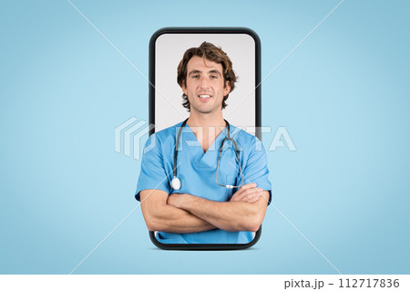 Smiling male nurse in blue scrubs inside smartphone frame with crossed arms 112717836