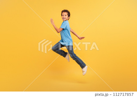 Black boy in mid-run on bright yellow background 112717857