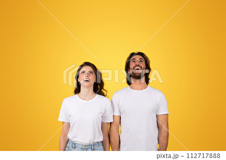 Excited man and woman in white shirts looking up in awe, their expressions full Excited man and woman in white shirts looking up in awe, their expressions full 112717888