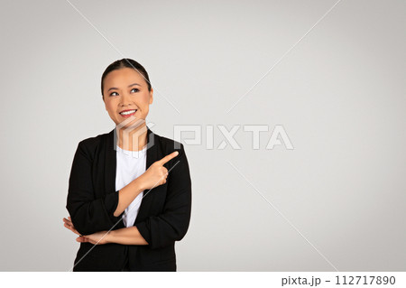 Confident Asian businesswoman with one arm crossed and the other pointing to the side 112717890
