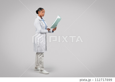 Focused black young woman doctor in white coat, work with papers 112717899