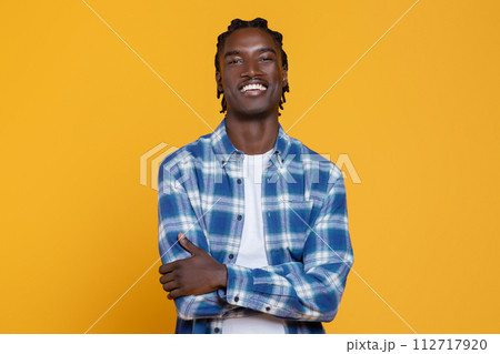 Handsome Young Black Man Posing With Folded Arms On Yellow Studio Background 112717920