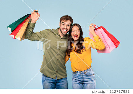 Cheerful couple celebrating shopping spree with colorful bags Cheerful couple celebrating shopping spree with colorful bags 112717921