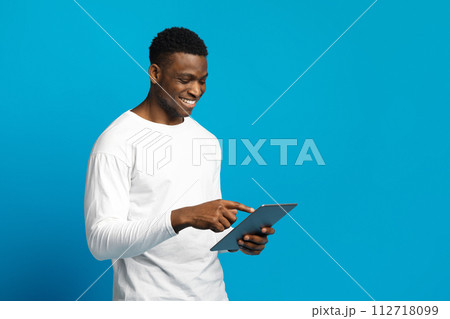 Happy young black guy using digital tablet 112718099