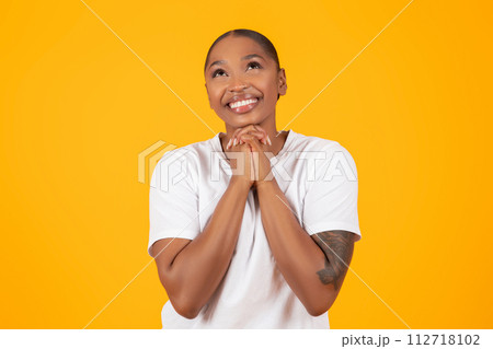 African American Woman Praying Holding Hands Together Over Yellow Backdrop 112718102