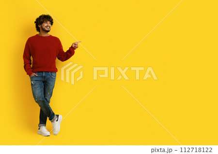 Happy millennial indian guy pointing at copy space Happy millennial indian guy pointing at copy space 112718122