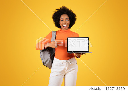 Excited young woman with an afro showcasing a laptop with a blank screen Excited young woman with an afro showcasing a laptop with a blank screen 112718450