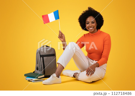 Smiling African American woman with curly hair sitting cross-legged on the floor 112718486