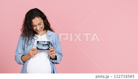 Happy pregnant woman showing ultrasound image of her baby Happy pregnant woman showing ultrasound image of her baby 112718565