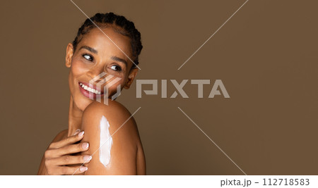 Joyful african american middle aged woman with lotion on shoulder 112718583