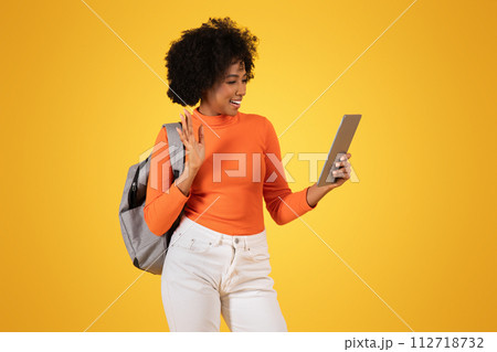 Cheerful African American woman waving during a video call on a tablet Cheerful African American woman waving during a video call on a tablet 112718732