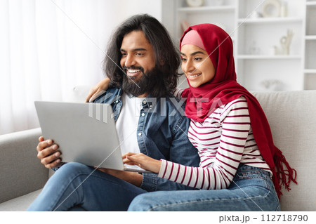 Portrait Of Happy Muslim Spouses Relaxing With Laptop At Home Portrait Of Happy Muslim Spouses Relaxing With Laptop At Home 112718790