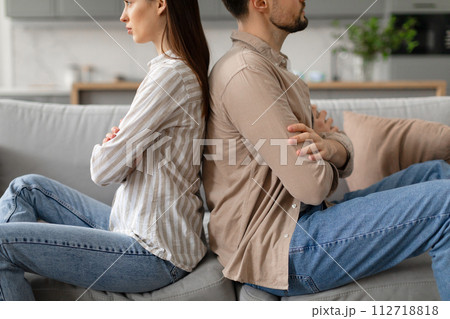 Spouses sitting on couch back to back, sulking after quarrel at home, cropped 112718818