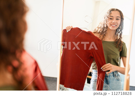 Happy stylish young lady selects perfect outfit in home closet 112718828
