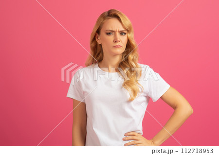 Displeased blonde lady expresses disapproval and frowning on pink background Displeased blonde lady expresses disapproval and frowning on pink background 112718953