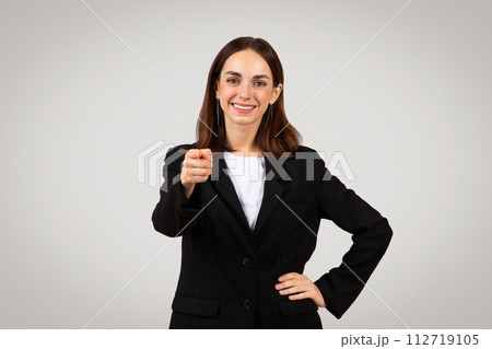 Professional, confident young woman in business attire pointing directly at camera with a friendly smile Professional, confident young woman in business attire pointing directly at camera with a friendly smile 112719105