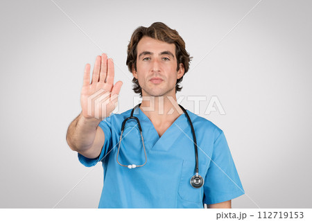Male medical professional in blue scrubs gesturing stop 112719153