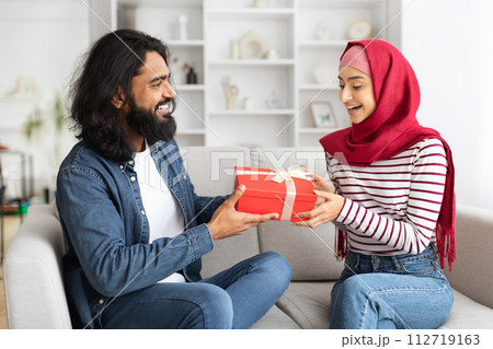 Arab man giving present to his excited muslim wife at home Arab man giving present to his excited muslim wife at home 112719163