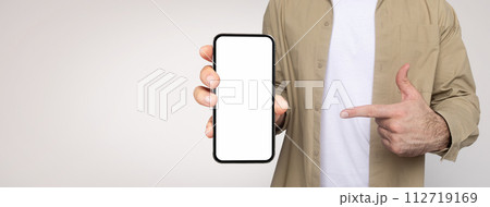 Man in a khaki shirt and white t-shirt holds a smartphone with the screen facing forward Man in a khaki shirt and white t-shirt holds a smartphone with the screen facing forward 112719169