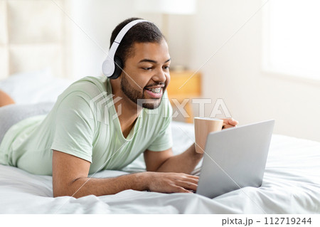 Relaxed black guy watching movie at home Relaxed black guy watching movie at home 112719244