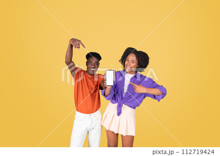 A young woman in a purple shirt and a young man in an orange shirt, both smiling 112719424