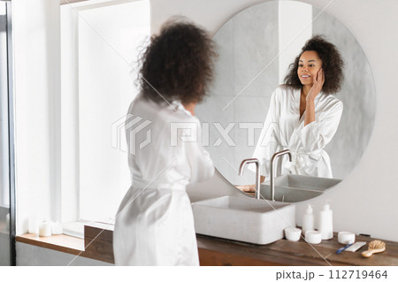 Beautiful black lady with perfect skin complexion touches face indoor Beautiful black lady with perfect skin complexion touches face indoor 112719464