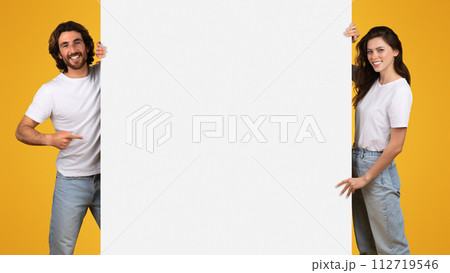 Cheerful young couple sharing a fun moment with a smartphone on a bright yellow background 112719546