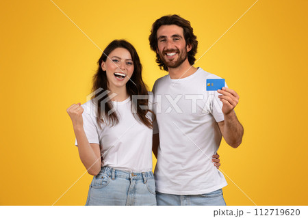Cheerful young woman and bearded man celebrating, with the man holding a blue credit card Cheerful young woman and bearded man celebrating, with the man holding a blue credit card 112719620