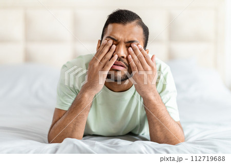 Upset broken african american young man crying in bed Upset broken african american young man crying in bed 112719688