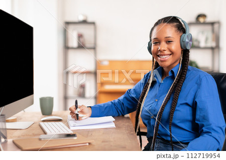 Confident black student lady with headphones studying at her desk 112719954