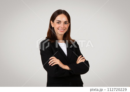 Confident young businesswoman with a pleasant smile, wearing a black suit and white shirt 112720229