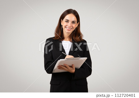 Confident young businesswoman with a warm smile writing on a digital tablet Confident young businesswoman with a warm smile writing on a digital tablet 112720401