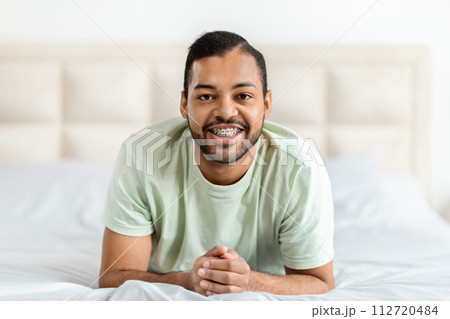 Closeup happy african american guy laying on bed at home 112720484
